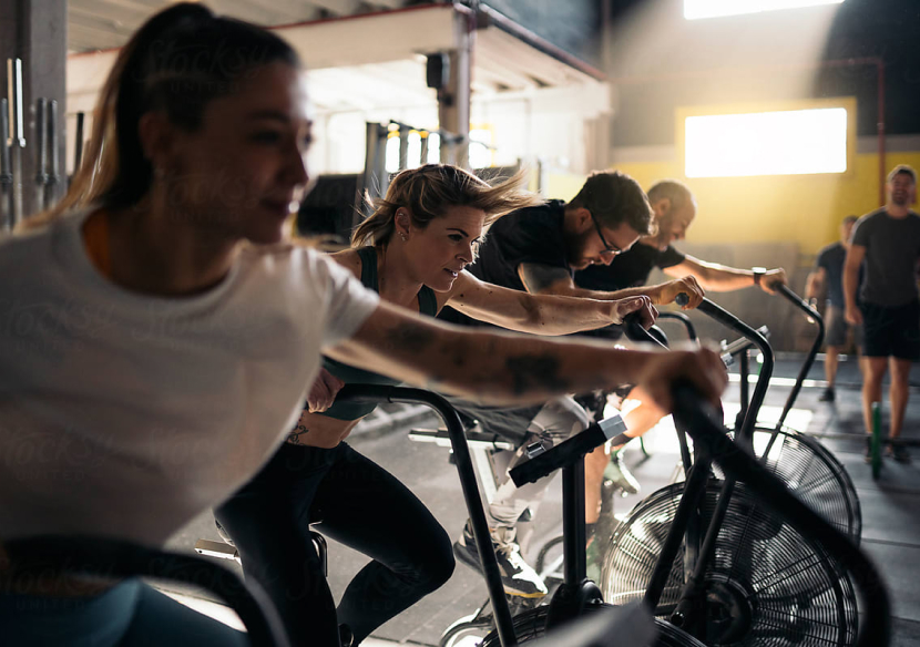 A group of people in a gym rigorously working out on stationary bikes